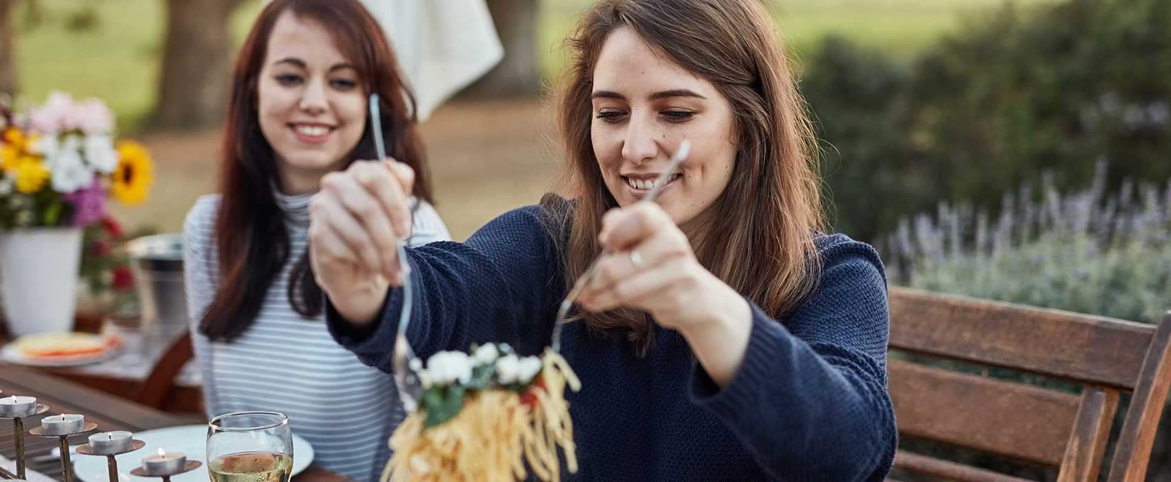 Woman putting pasta on her plate.