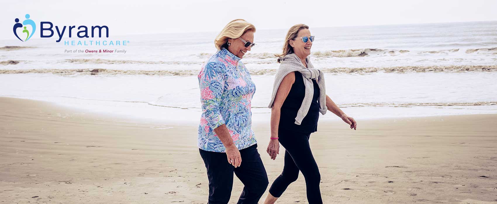 Two women walking on a beach.