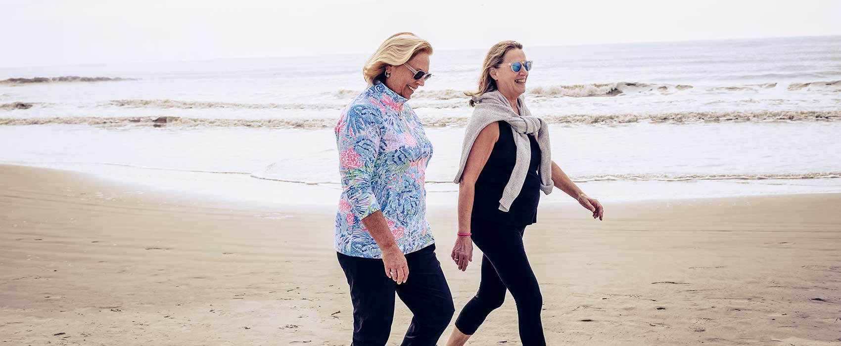 Two women walking on a beach.