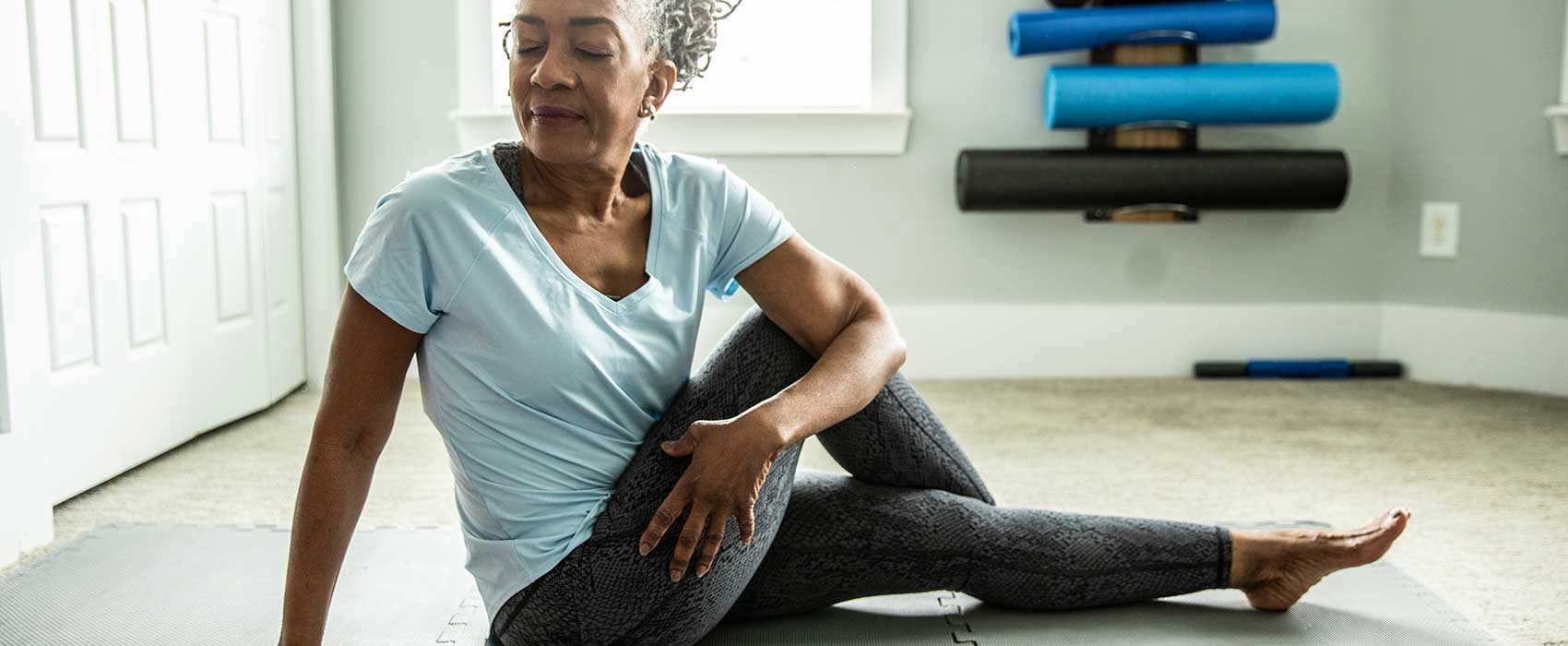 Older woman stretching on a mat.