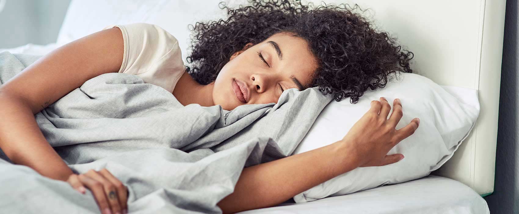 Woman sleeping in a white bed.