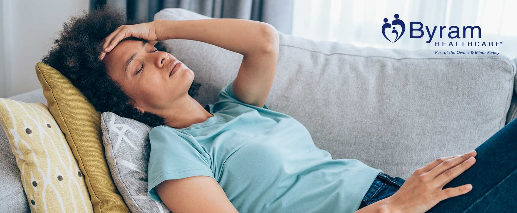 Woman laying on a couch looking uncomfortable.