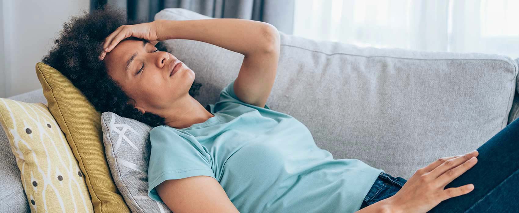 Woman laying on a couch looking uncomfortable.
