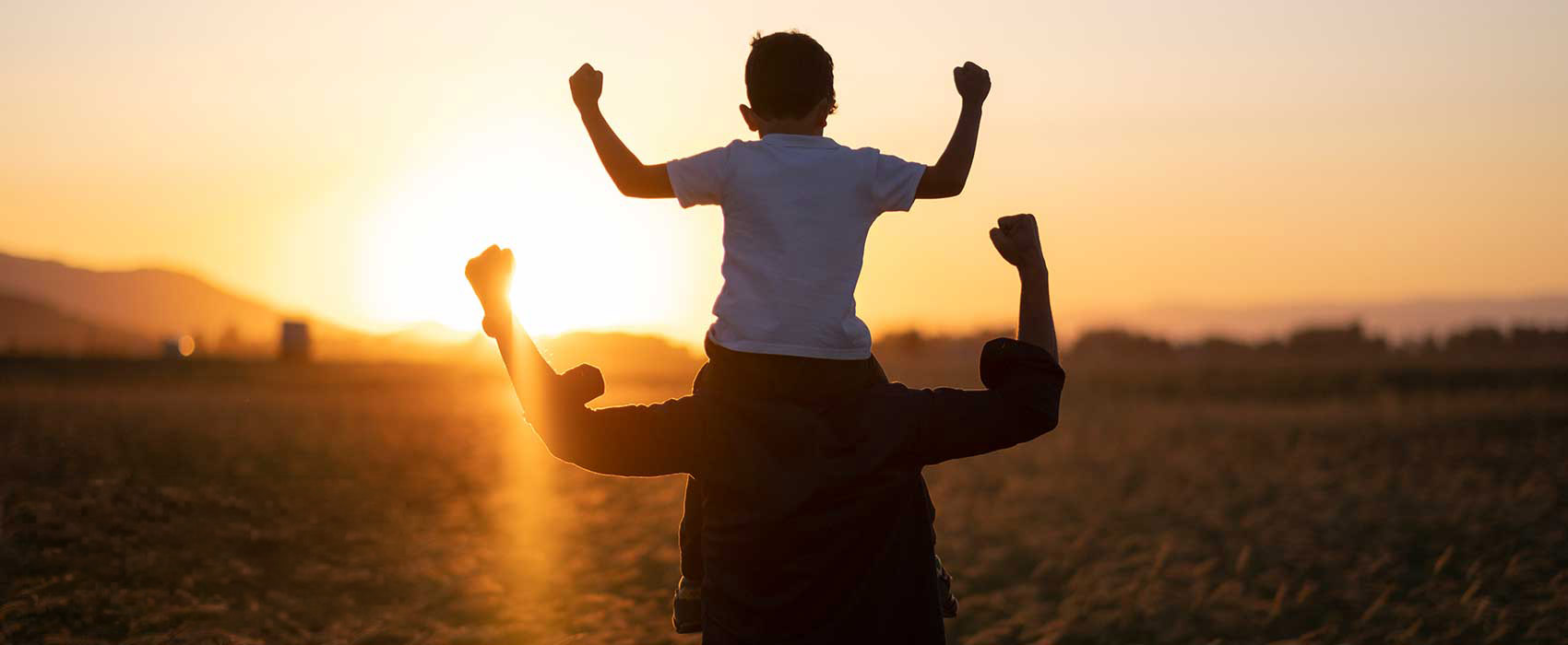 Father walking with son on his shoulders.