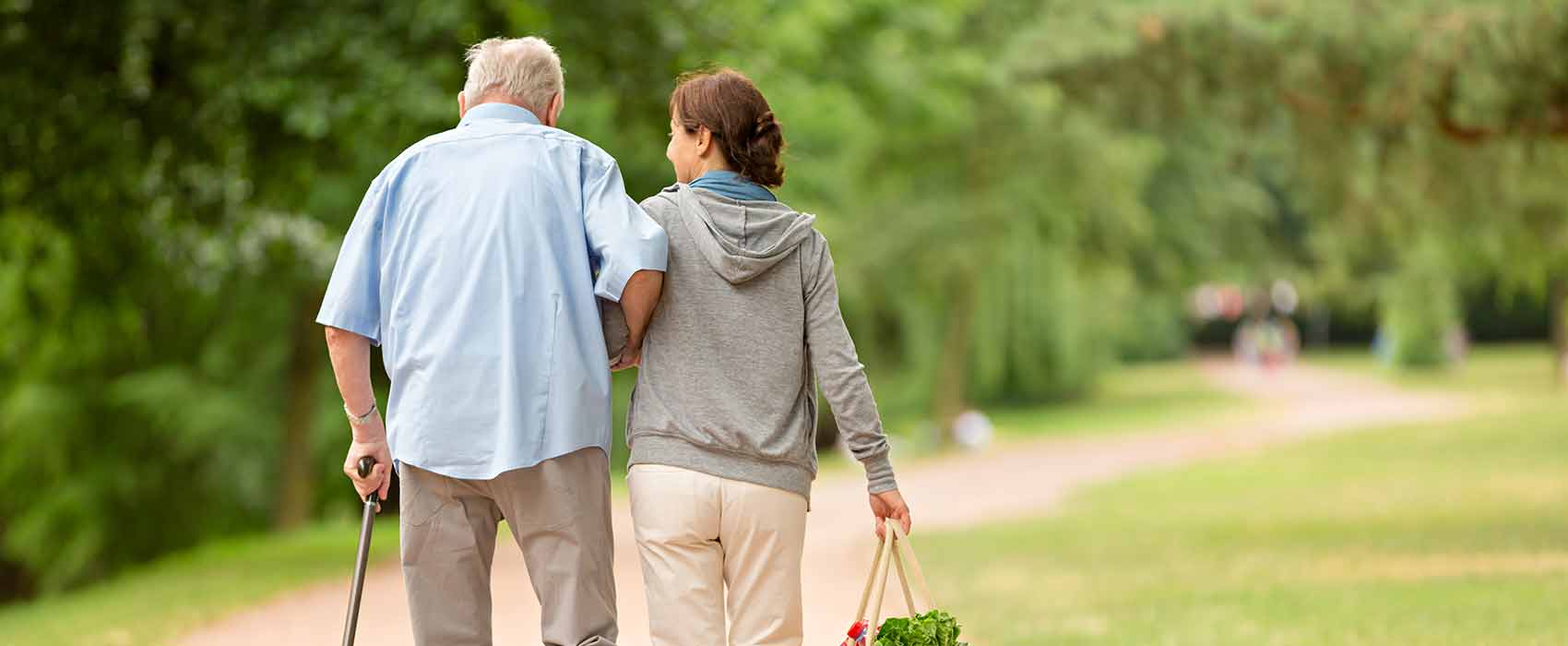 Caregiver helping an old man walk.