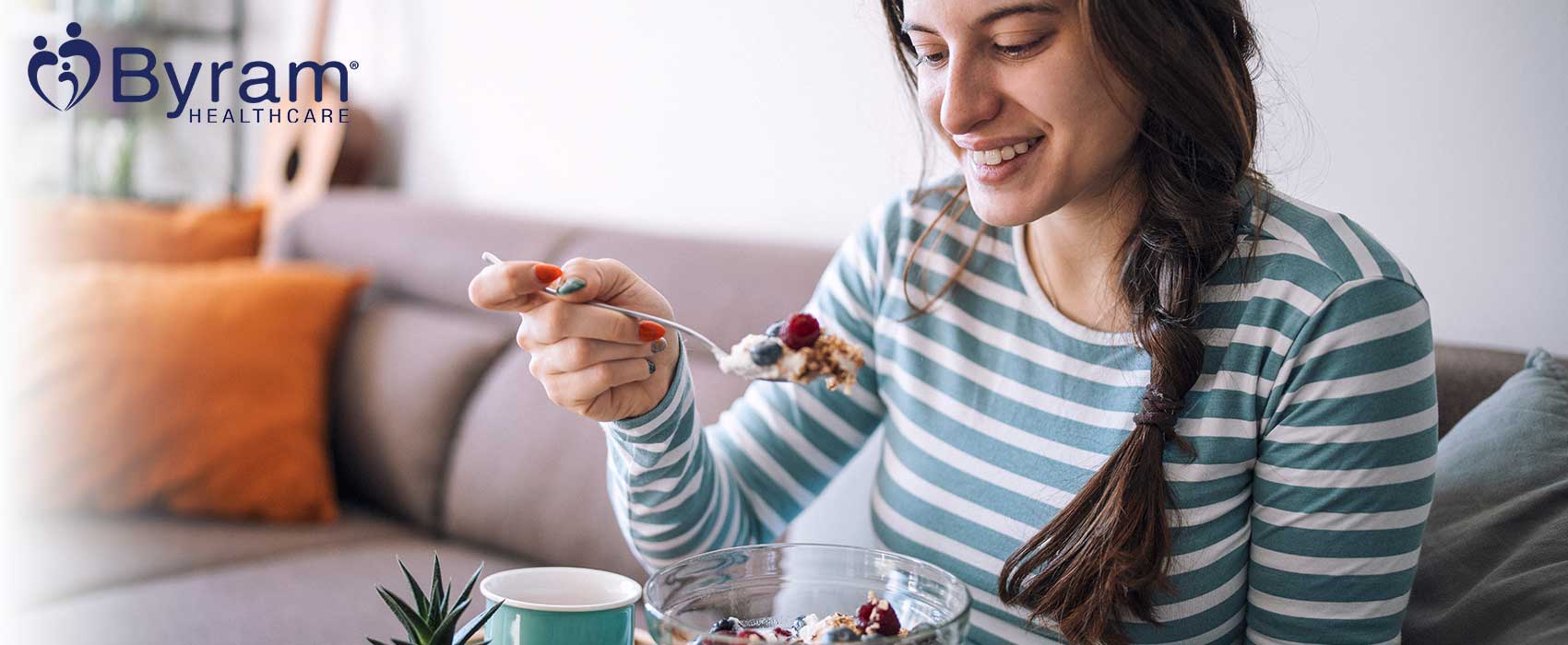 Woman eating a fruit bowl on her couch.