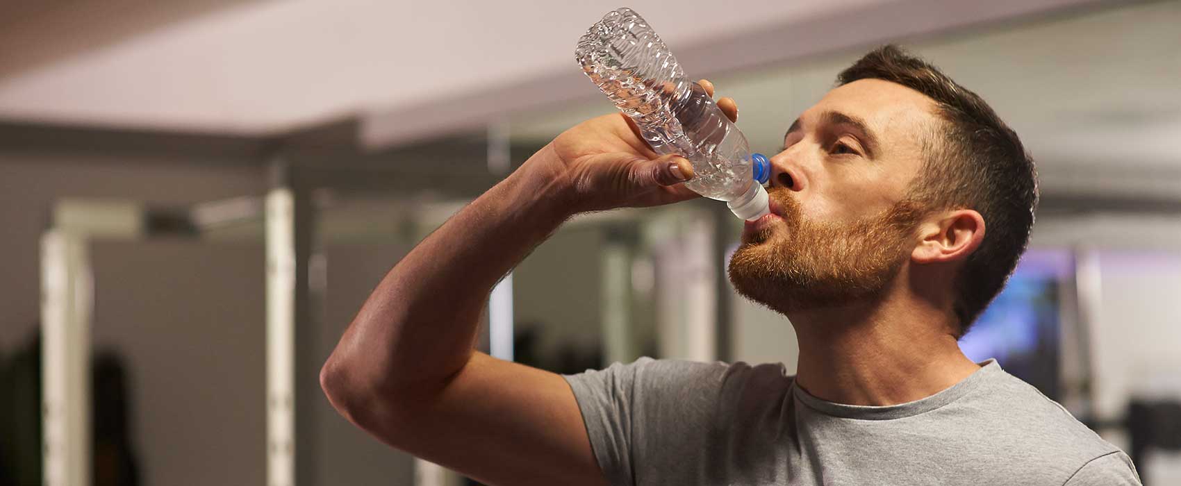 Man drinking a bottle of water at the gym.