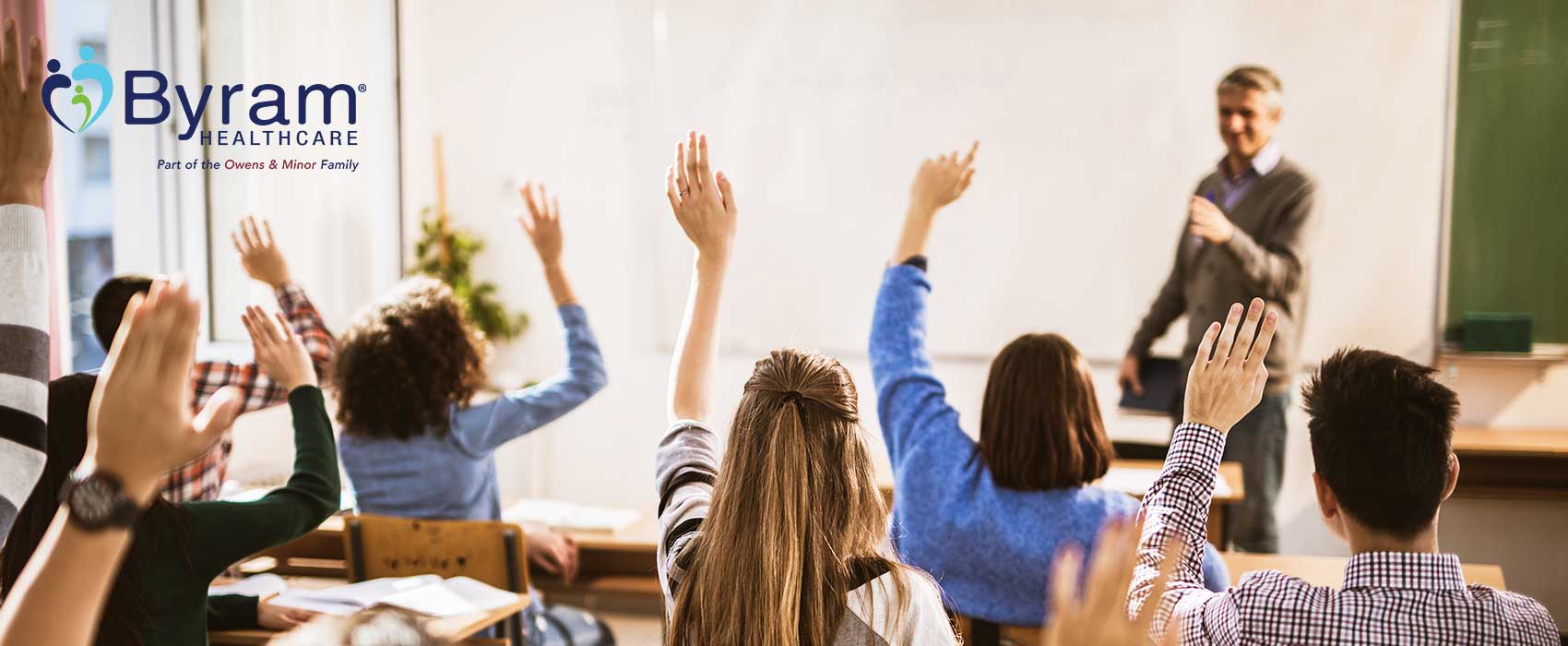 Kids in a classroom raising their hands.