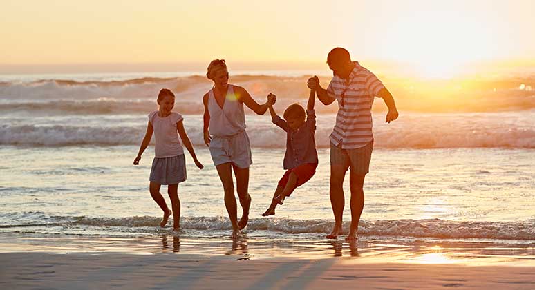 Family walking on the beach during sunset.