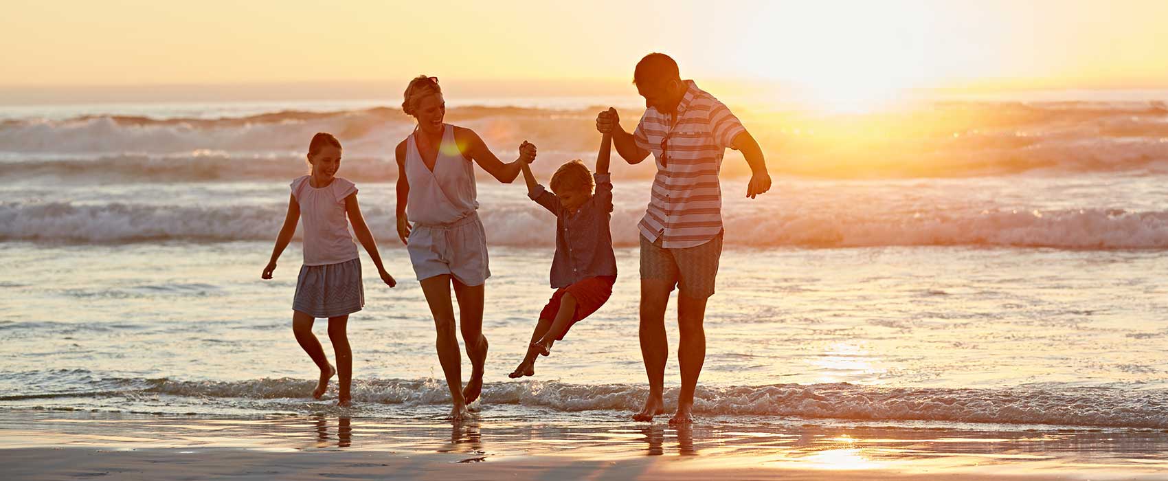 Family walking on the beach during sunset.