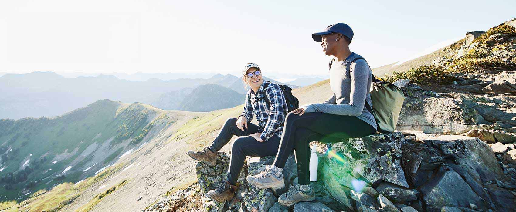 Two people sitting on a mountain.