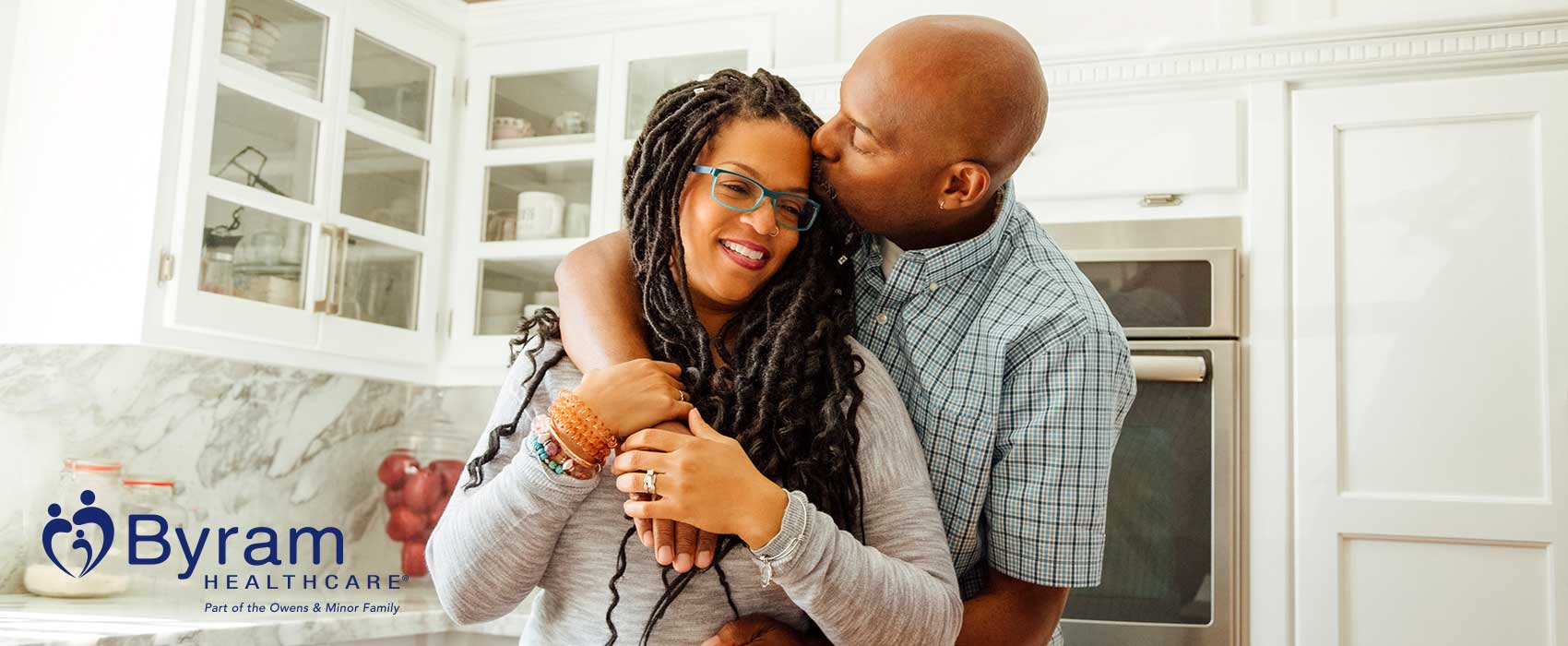 Couple hugging in their kitchen.