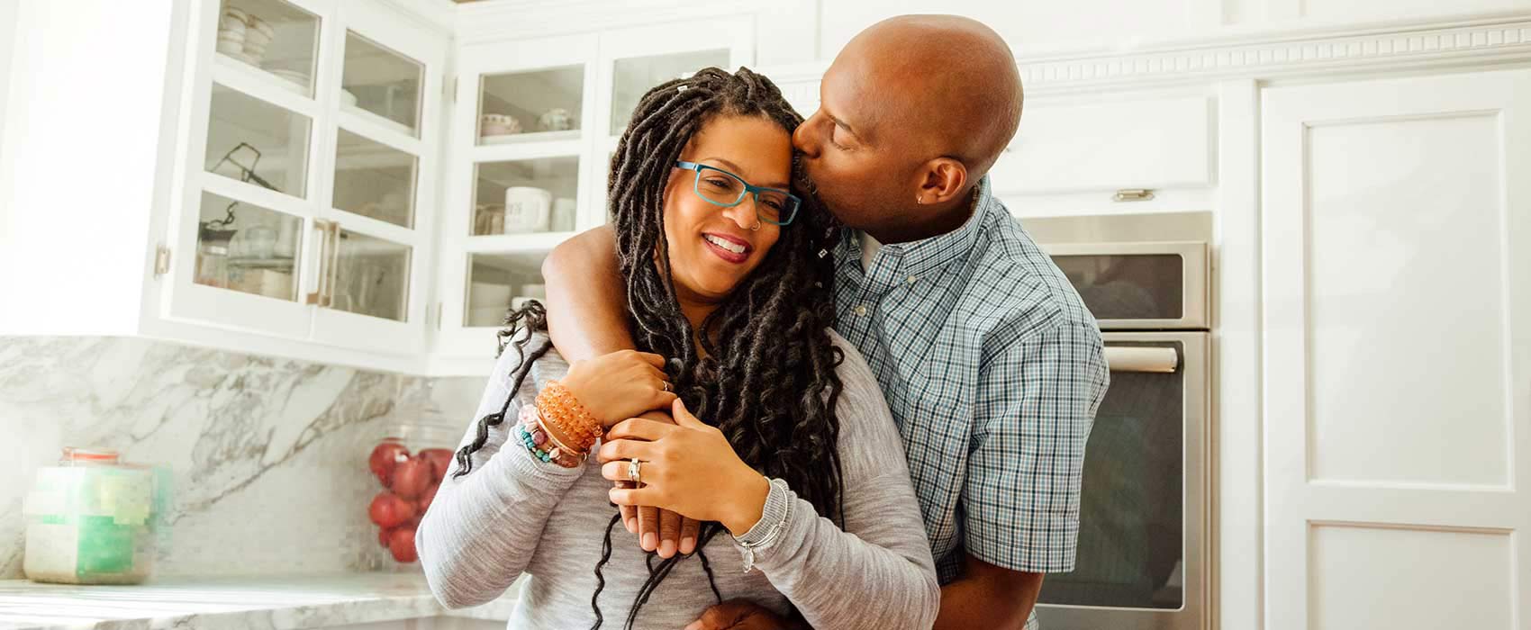 Couple hugging in their kitchen.