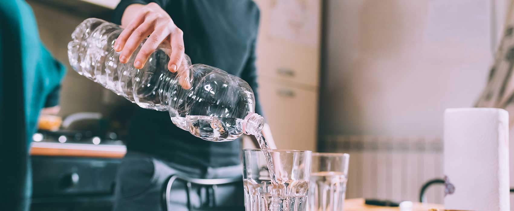 Person pouring a glass of water.