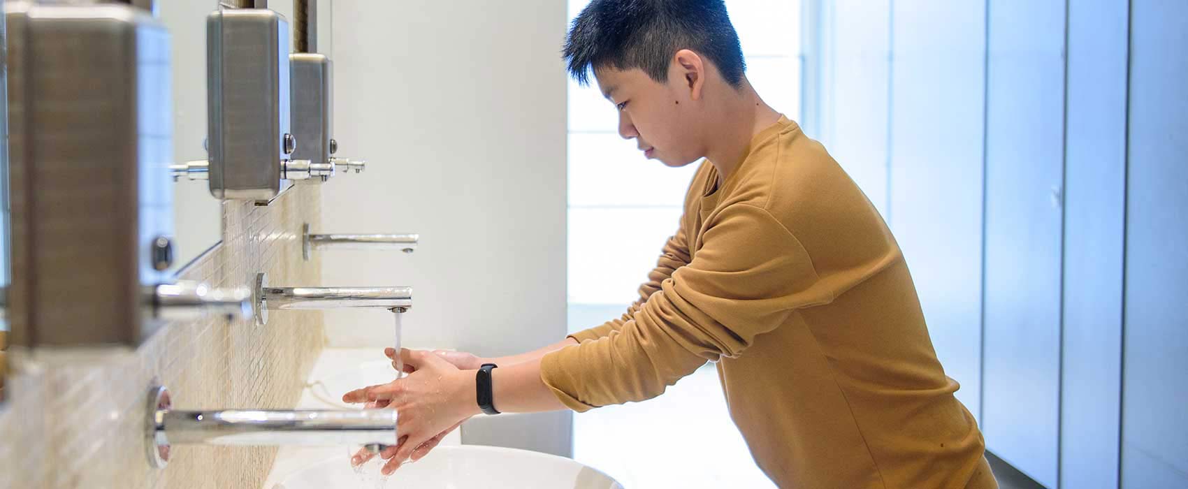 Man washing his hands in a public restroom