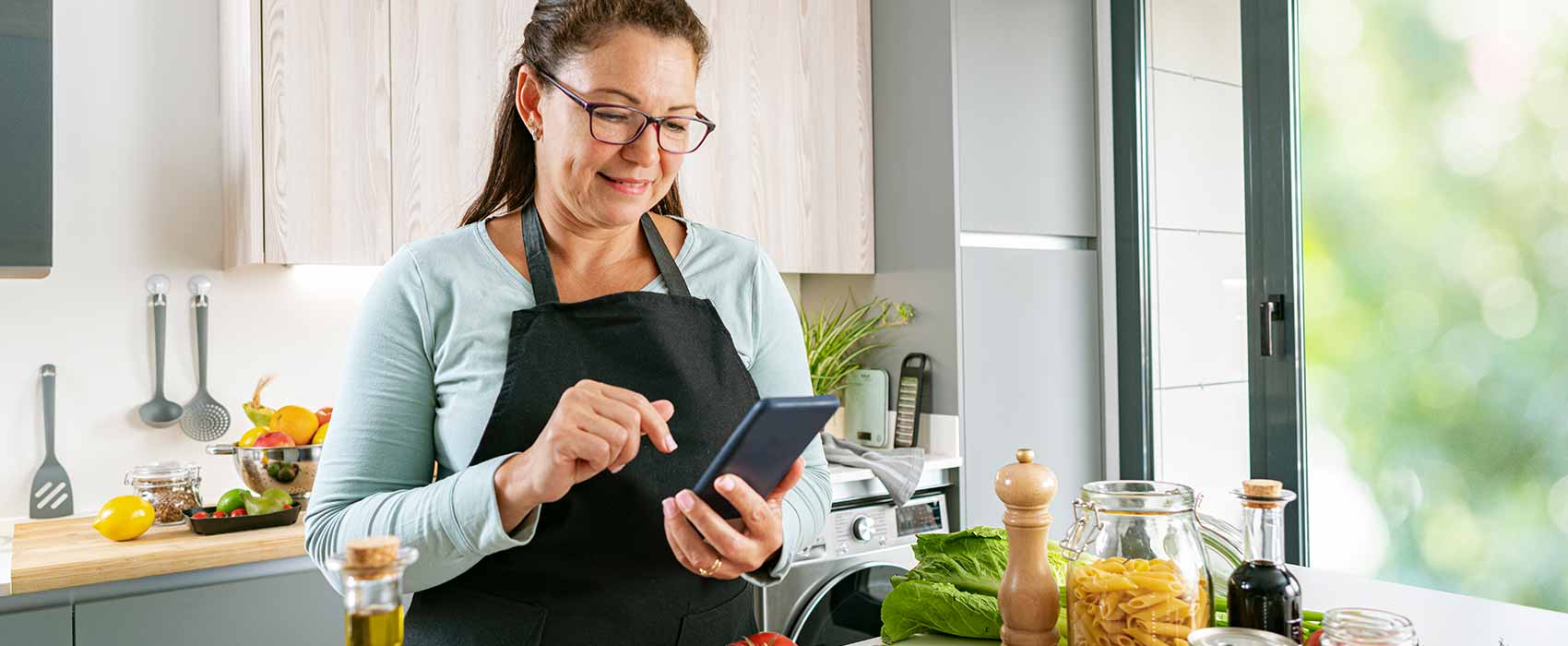 Woman in the kitchen looking at her phone.