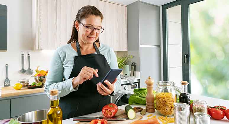 Woman in the kitchen looking at her phone.