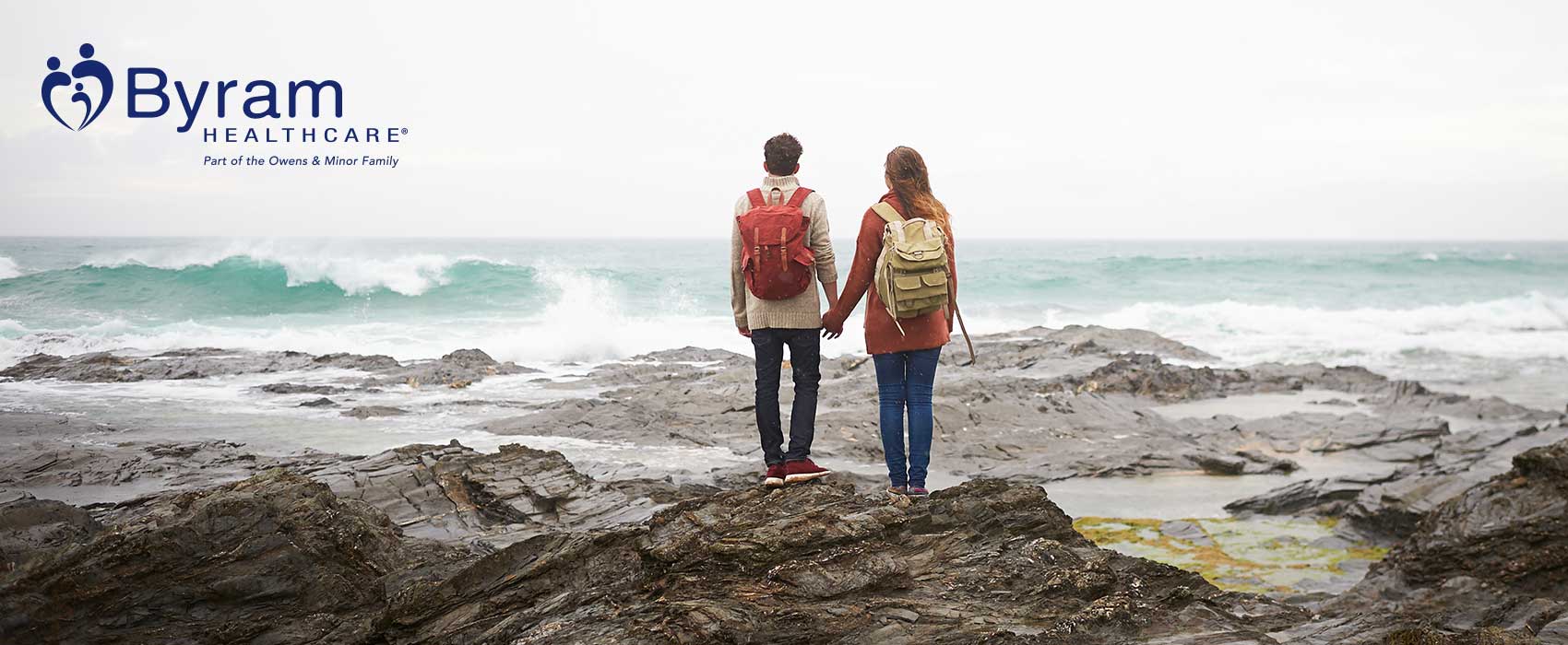 Couple holding hands on beachy rocks.