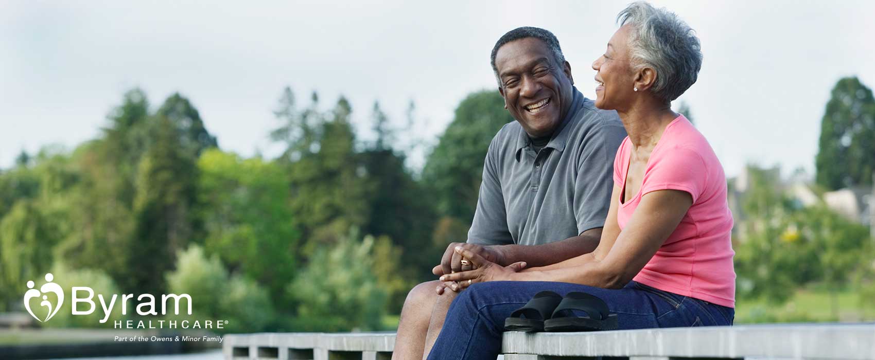 Man and woman sitting on a dock while laughing.