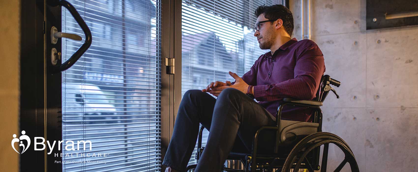 Man in his wheelchair looking out a window.