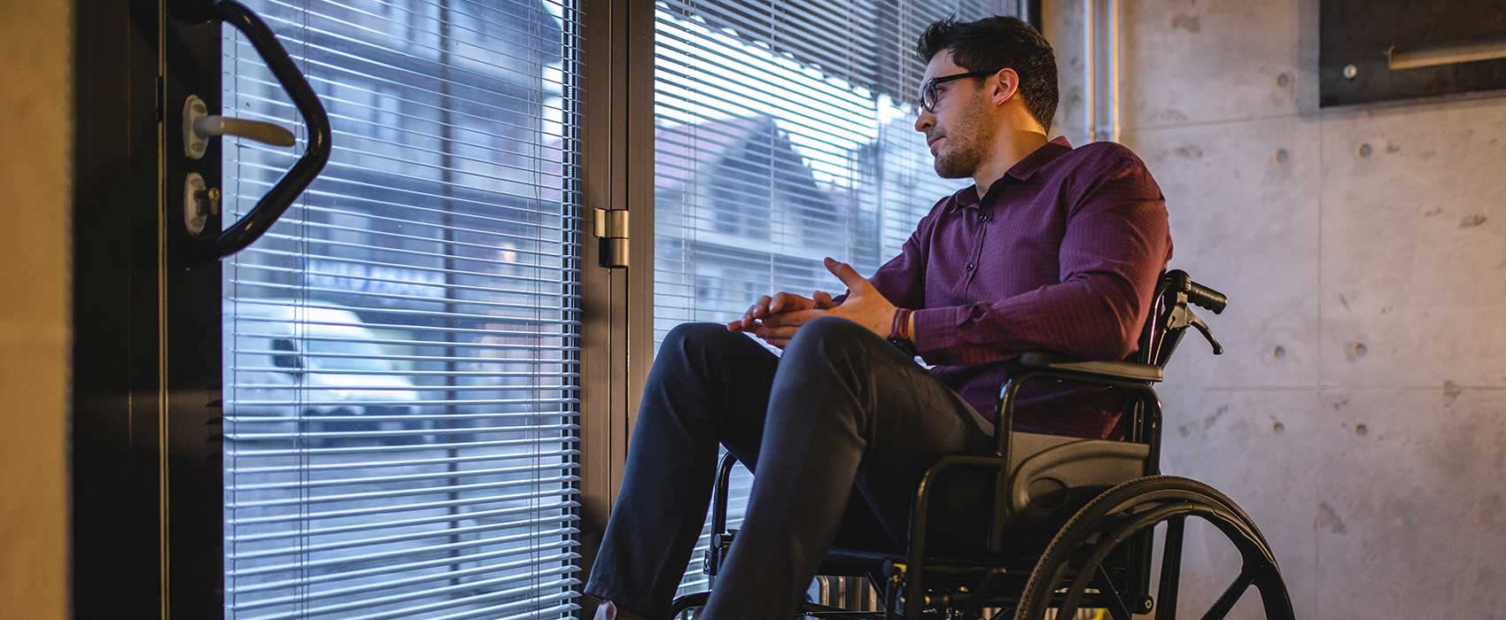 Man in his wheelchair looking out a window.