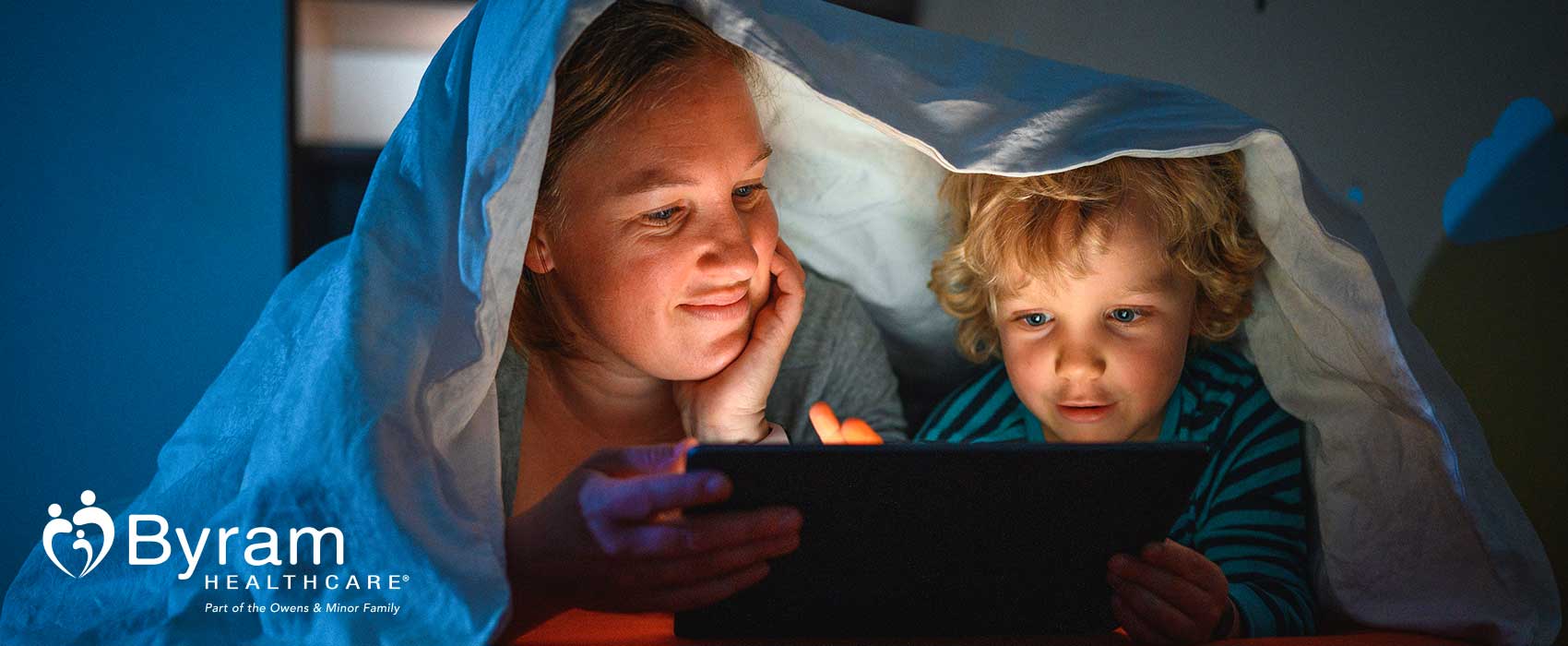 Mom and son reading a bedtime story on a tablet.