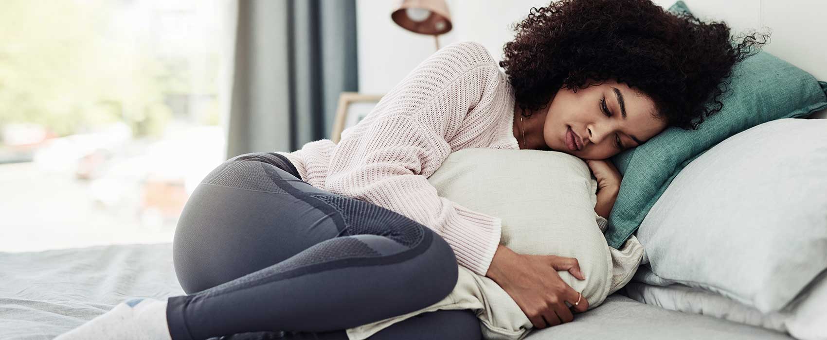 Woman in pain laying on her side.