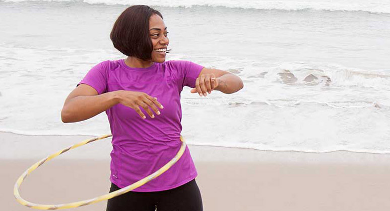 Woman hula-hooping on the beach