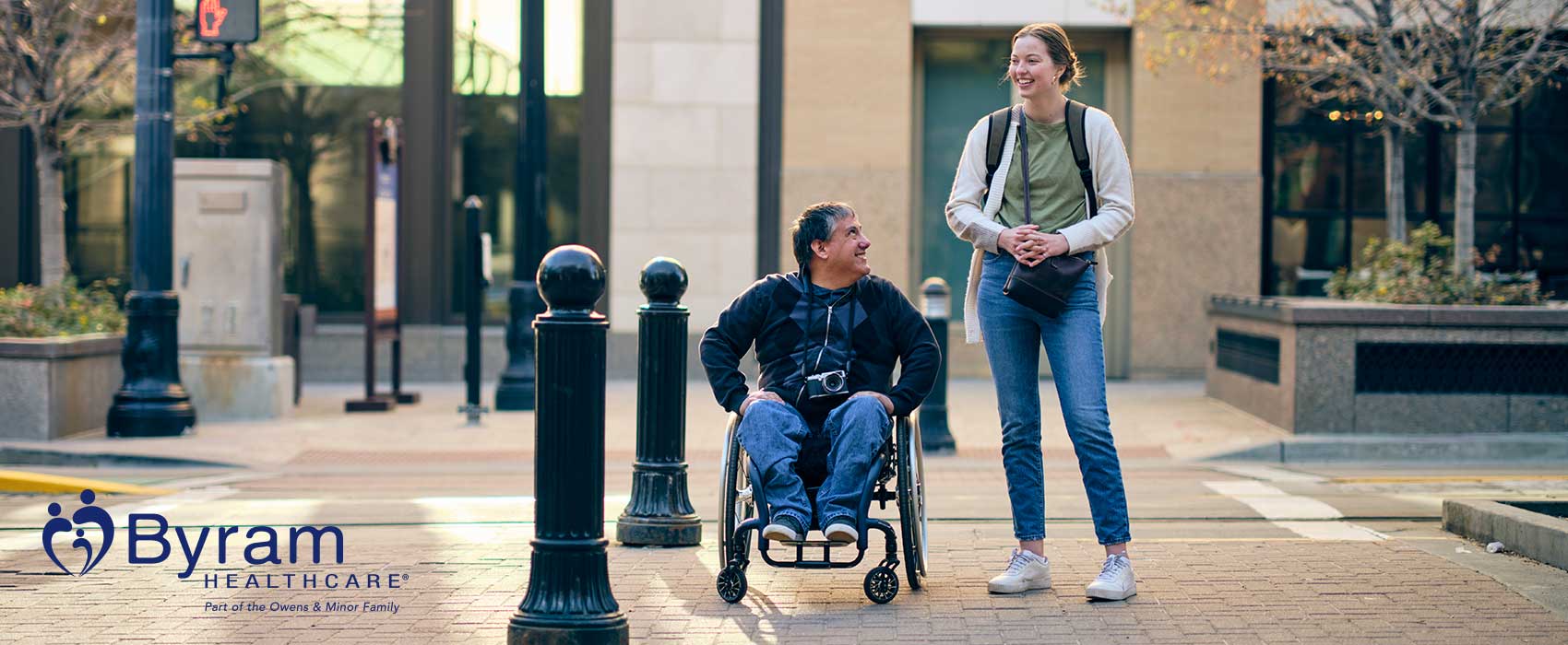 Woman walking with man in wheelchair.