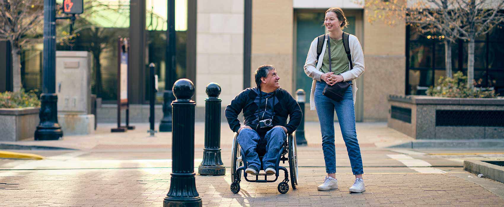 Woman walking with man in wheelchair.