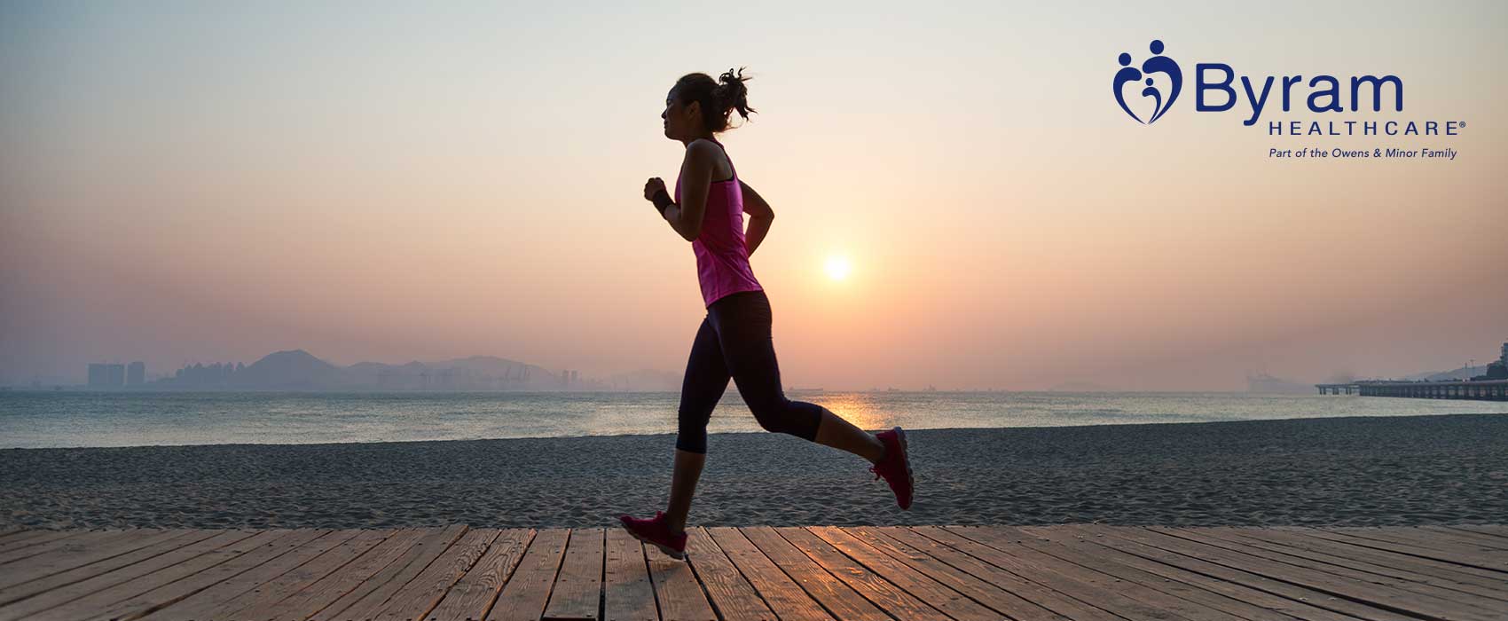Woman jogging on a boardwalk during sunset.