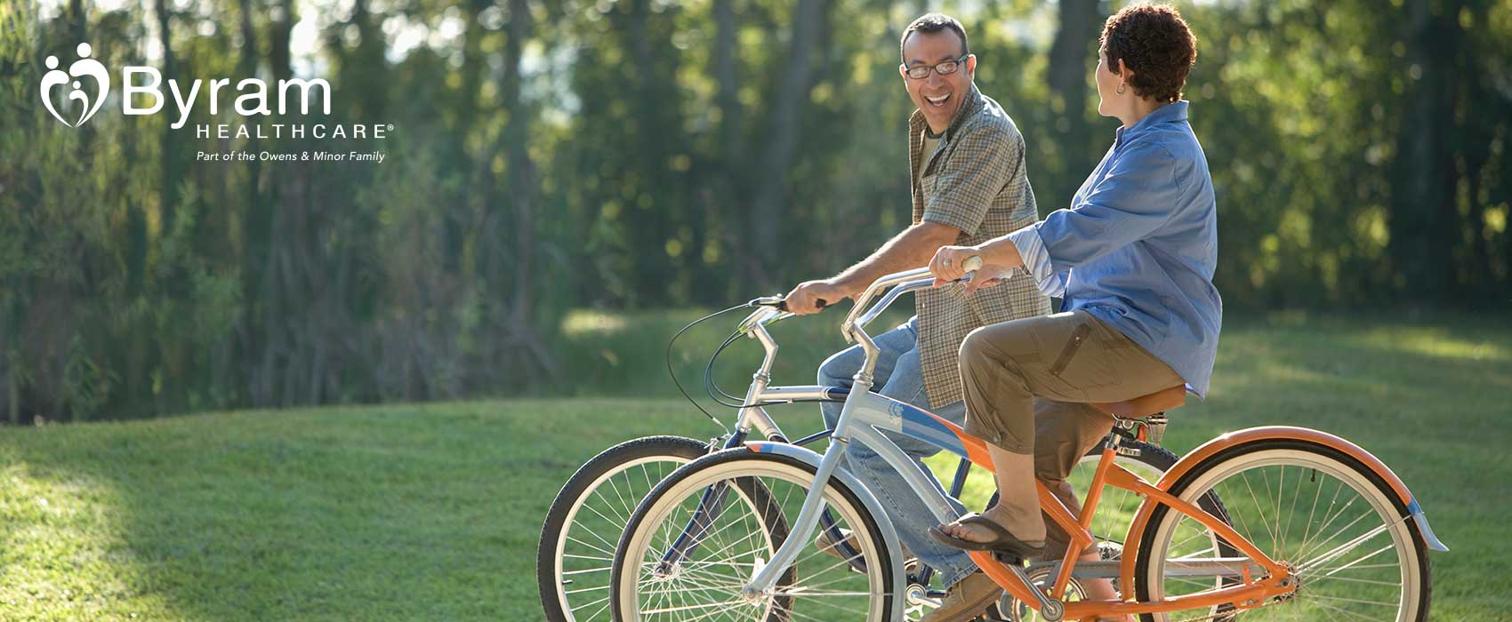 Couple riding their bikes through the woods.