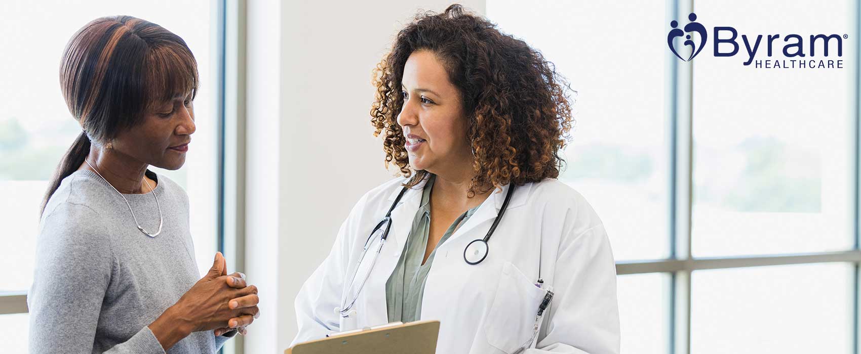 Urologist talking to her patient, using a clipboard.