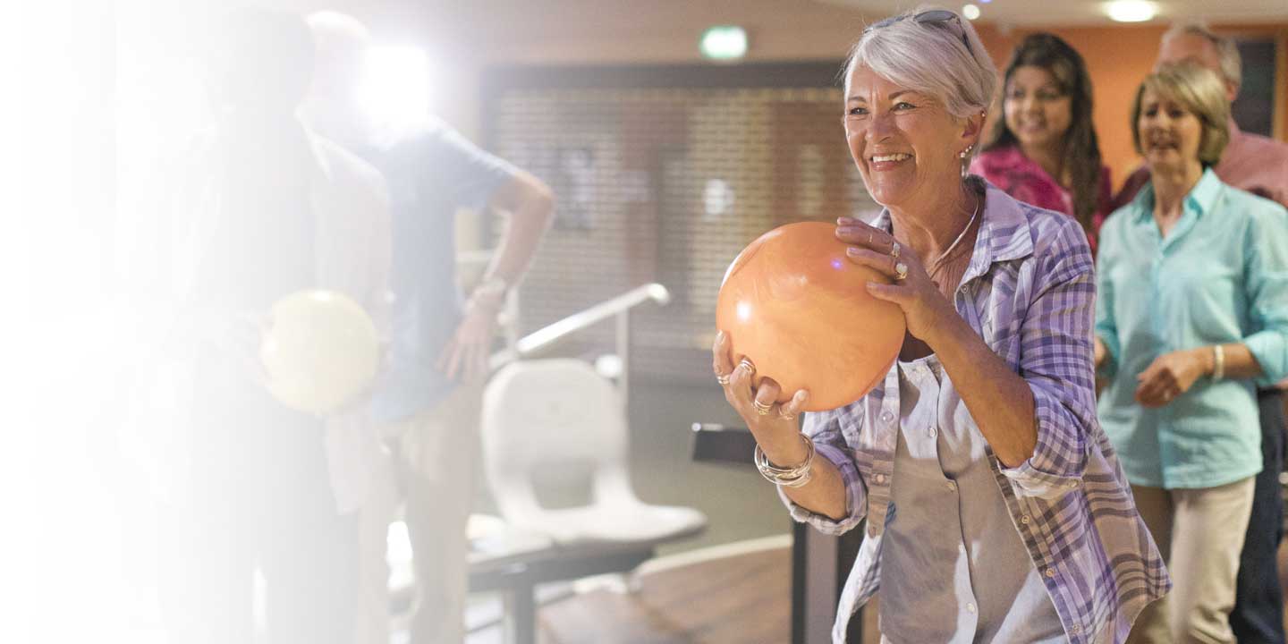 Mujer mayor jugando a los bolos con amigos