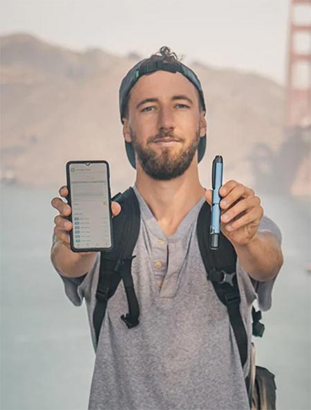 Man Backpacking Holding Medtronic InPen and Mobile Phone