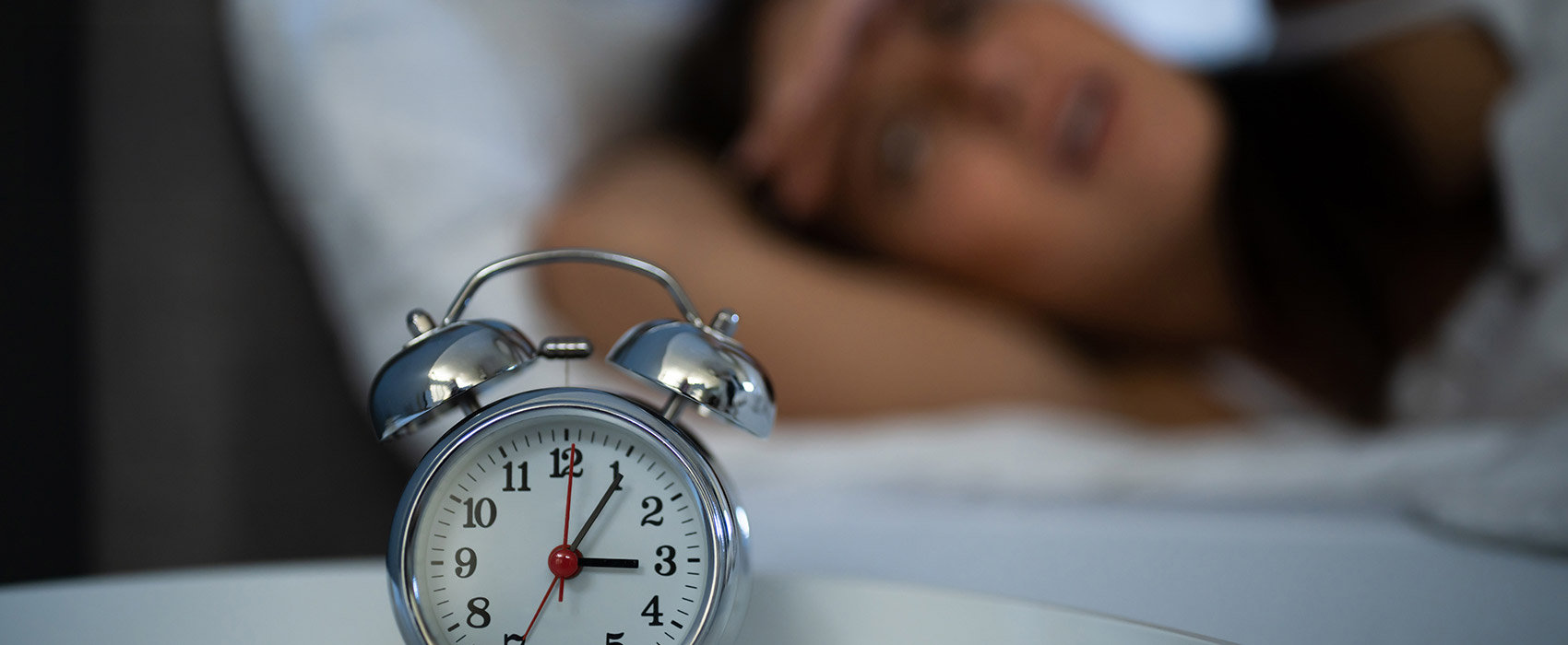 person sleeping with clock next to bed