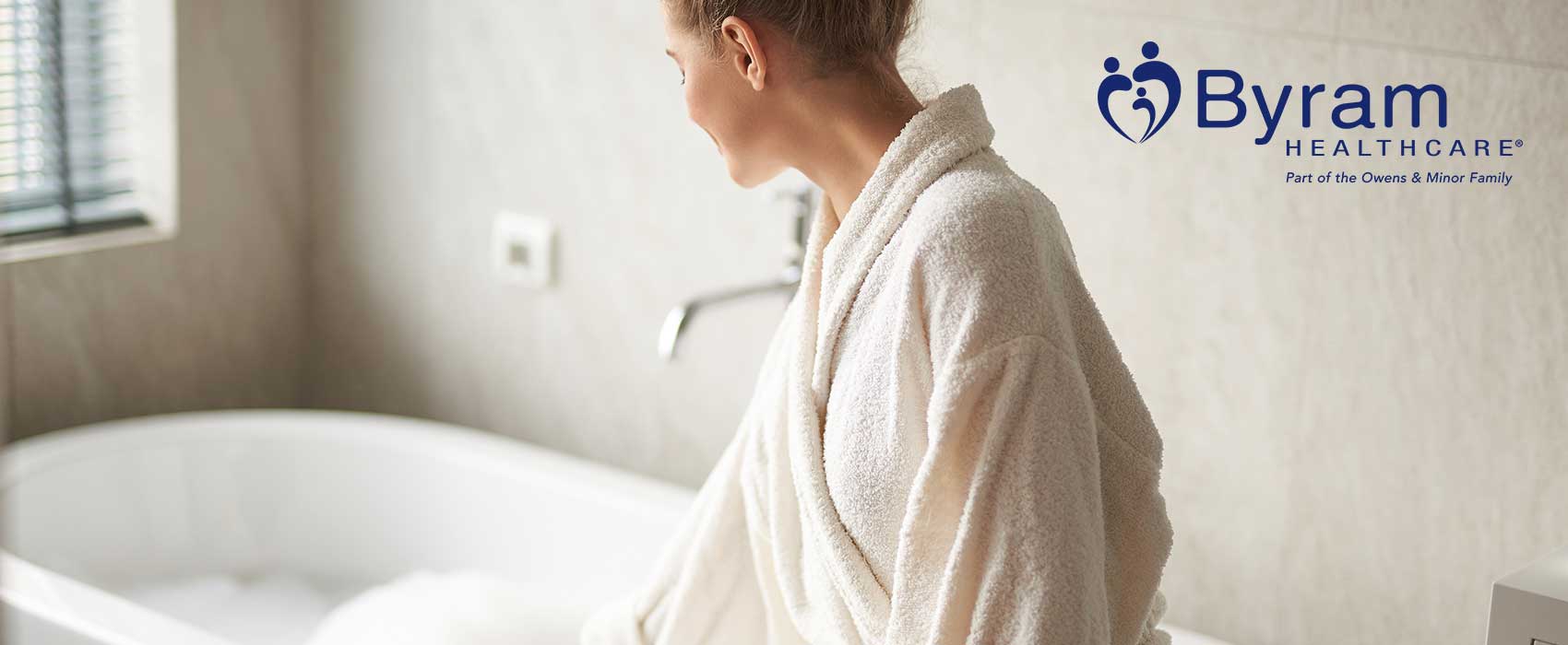 woman in bathrobe sitting beside a tub