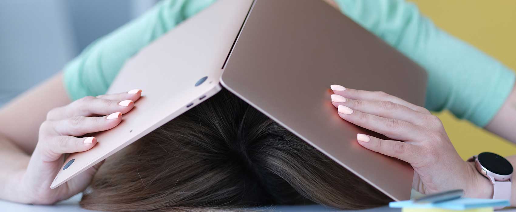 woman covering head with laptop