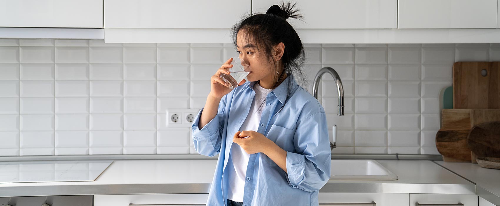 woman drinking water in kitchen