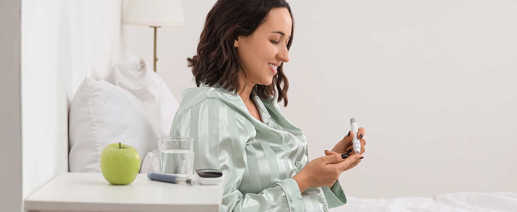 woman in bed checking blood glucose